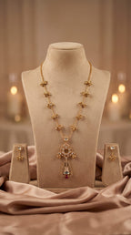 Gold necklace with a cross pendant on a mannequin bust, with earrings displayed below, against a soft blurred background.